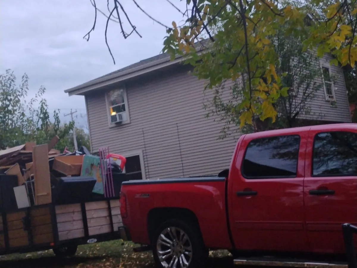 Pickup truck and trailer hauling a full junk removal load
