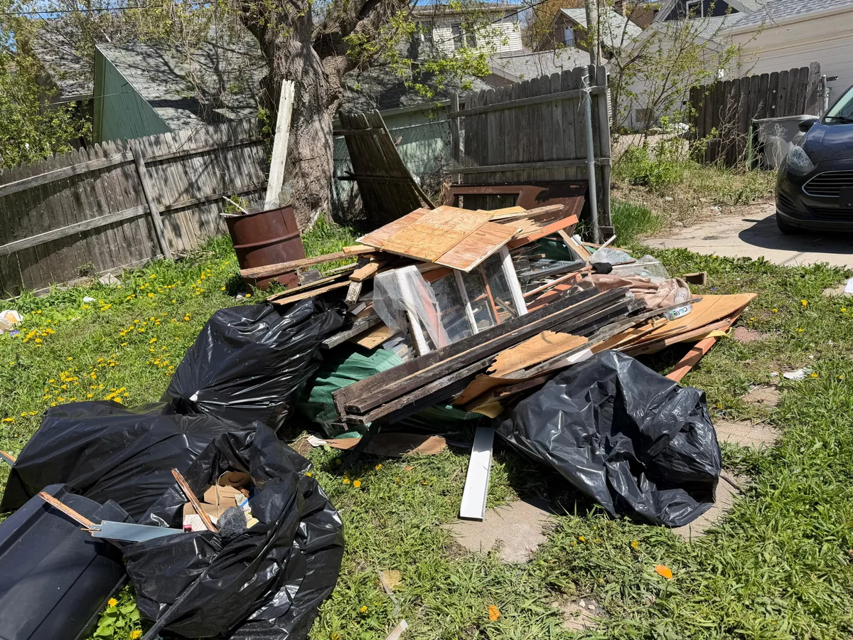 Backyard debris pile of scrap wood and trash bags for removal